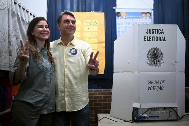 Brazil's right-wing senator and Liberal Party (PL) presidential candidate Flavio Bolsonaro and his wife Fernanda Bolsonaro make V-for-victory signs during the presidential runoff election at a polling station in Rio de Janeiro, Brazil, on October 25, 2026. Flavio Bolsonaro faces President Luiz Inacio Lula da Silva in a runoff that will determine whether Brazil remains one of the few leftist nations in the region or joins a regional swing to the right championed by his ally, US President Donald Trump. (Photo by MAURO PIMENTEL / AFP)