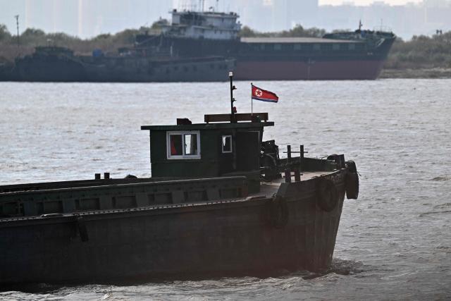 A boat flying a North Korean flag sails on the Yalu River between the North Korean town of Sinuiju and the Chinese city of Dandong, in China's northeast Liaoning province, on October 25, 2026.  (Photo by Pedro PARDO / AFP)