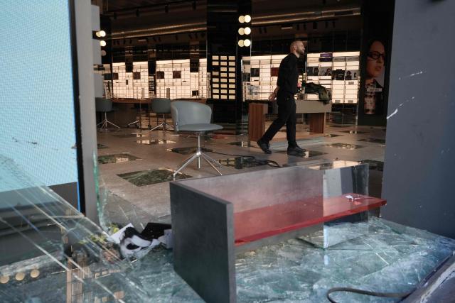An employee inspects an optician's shop looted the previous night during riots, in Barcelona on October 25, 2026. Police made 128 arrests overnight in Barcelona for acts of "vandalism", damage to public property" and "looting", the regional Catalan police said today. Seventy-three of those arrested were minors, with the reports due to be sent "to the juvenile prosecutor's office", Catalan police chief Silvia Cata told Spain's 3CatInfo media outlet. (Photo by Manaure QUINTERO / AFP)