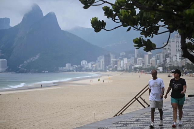 Locals walk at Ipanema beach in Rio de Janeiro, Brazil, on October 25, 2026, on the day of the presidential runoff election. Brazilians head to the polls for a runoff between President Luiz Inacio Lula da Silva and right-wing senator Flavio Bolsonaro that will determine whether Brazil remains one of the few leftist nations in the region or joins a regional swing to the right championed by US President Donald Trump, a Bolsonaro ally. (Photo by MAURO PIMENTEL / AFP)