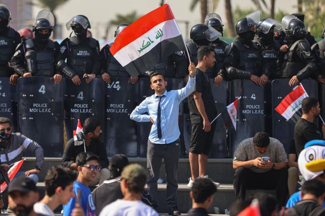 Riot police watch protesters as they gather in Baghdad's Tahrir Square on October 25, 2026 to mark the 7th anniversary of the 2019 Iraqi anti-government demonstrations. (Photo by AHMAD AL-RUBAYE / AFP)