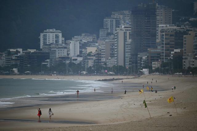 People walk at Ipanema beach in Rio de Janeiro, Brazil, on October 25, 2026, on the day of the presidential runoff election. Brazilians head to the polls for a runoff between President Luiz Inacio Lula da Silva and right-wing senator Flavio Bolsonaro that will determine whether Brazil remains one of the few leftist nations in the region or joins a regional swing to the right championed by US President Donald Trump, a Bolsonaro ally. (Photo by MAURO PIMENTEL / AFP)