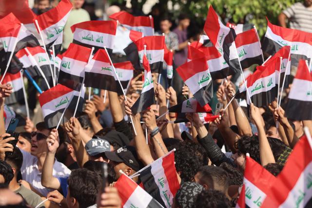 Protesters wave flags of Iraq as they gather in Baghdad's Tahrir Square on October 25, 2026 to mark the 7th anniversary of the 2019 Iraqi anti-government demonstrations. (Photo by AHMAD AL-RUBAYE / AFP)
