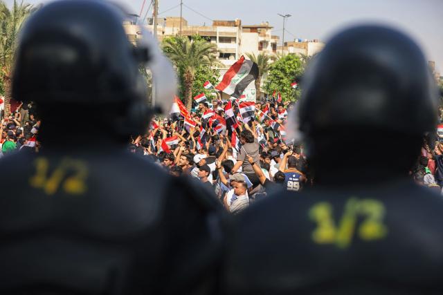 Riot police watch protesters as they gather in Baghdad's Tahrir Square on October 25, 2026 to mark the 7th anniversary of the 2019 Iraqi anti-government demonstrations. (Photo by AHMAD AL-RUBAYE / AFP)