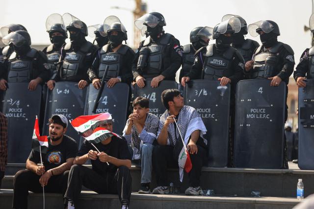 Riot police watch protesters as they gather in Baghdad's Tahrir Square on October 25, 2026 to mark the 7th anniversary of the 2019 Iraqi anti-government demonstrations. (Photo by AHMAD AL-RUBAYE / AFP)