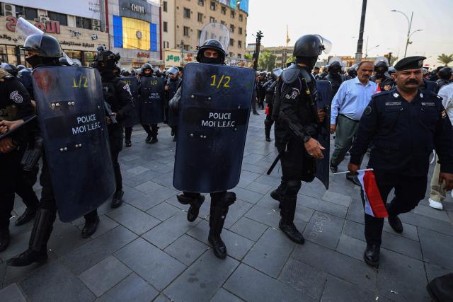 Riot police watch protesters as they gather in Baghdad's Tahrir Square on October 25, 2026 to mark the 7th anniversary of the 2019 Iraqi anti-government demonstrations. (Photo by AHMAD AL-RUBAYE / AFP)