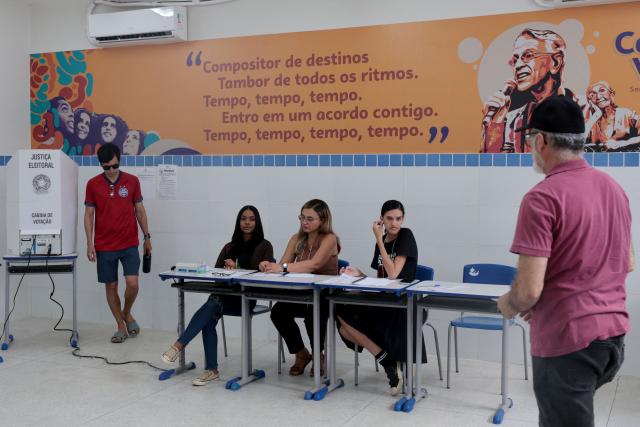 People vote at a polling station during the presidential runoff election in Salvador, Bahia state, Brazil, on October 25, 2026. Brazilians head to the polls for a runoff between President Luiz Inacio Lula da Silva and right-wing senator Flavio Bolsonaro that will determine whether Brazil remains one of the few leftist nations in the region or joins a regional swing to the right championed by US President Donald Trump, a Bolsonaro ally. (Photo by Antonello VENERI / AFP)