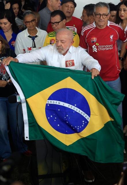 Brazil's President and re-election candidate for the Workers' Party (PT) Luiz Inacio Lula da Silva hols a Brazilian national flag after casting his vote during the presidential runoff election, at a polling station in Sao Bernardo do Campo, state of Sao Paulo, Brazil, on October 25, 2026. Lula da Silva faces right-wing senator Flavio Bolsonaro in a runoff that will determine whether Brazil remains one of the few leftist nations in the region or joins a regional swing to the right championed by US President Donald Trump, Bolsonaro's ally. (Photo by Miguel SCHINCARIOL / AFP)