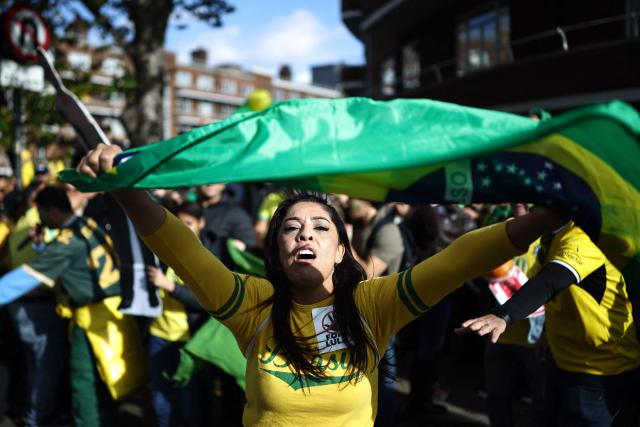 Supporters of Flavio Bolsonaro sing and dance outside the vote centre as voters arrive to cast their ballots in the Brazilian presidential election runoff at West London College, on October 25, 2026. The election outcome could see Latin America's largest country join a regional shift to the right championed by the US President, or remain a left-wing stronghold. (Photo by Henry NICHOLLS / AFP)