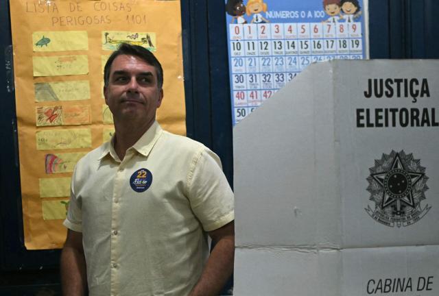Brazil's right-wing senator and Liberal Party (PL) presidential candidate Flavio Bolsonaro walks past a classroom display reading "List of Dangerous Things" after casting his ballot during the presidential runoff election at a polling station in Rio de Janeiro, Brazil, on October 25, 2026. Flavio Bolsonaro faces President Luiz Inacio Lula da Silva in a runoff that will determine whether Brazil remains one of the few leftist nations in the region or joins a regional swing to the right championed by his ally, US President Donald Trump. (Photo by MAURO PIMENTEL / AFP)
