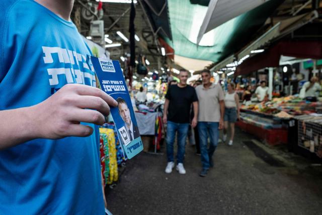 HaDemokratim (The Democrats) party leader Yair Golan's supporters campaign in a market area in Tel Aviv on October 25, 2026, ahead of Israel's legislative election. Israel heads to the polls on October 27 in its first election since the October 7, 2023 Hamas-led attack, in what is seen as a referendum on the prime minister. (Photo by Jewel SAMAD / AFP)