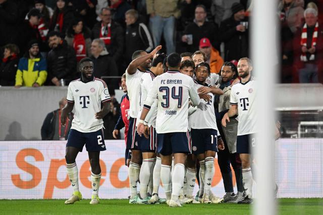 Team mates celebrate Bayern Munich's French midfielder #17 Michael Olise (hidden) after he scored the 1:3 goal during the German first division Bundesliga football match between SC Freiburg and FC Bayern Munich in Freiburg, south-western Germany, on October 25, 2026. (Photo by THOMAS KIENZLE / AFP) / DFL REGULATIONS PROHIBIT ANY USE OF PHOTOGRAPHS AS IMAGE SEQUENCES AND/OR QUASI-VIDEO