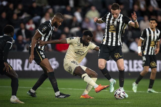 Lorient's French forward #18 Ibrahima Balde clears the ball next to Angers's Malian defender #04 Ousmane Camara and Angers's Dutch midfielder #08 Branco van den Boomen during the French L1 football match between SCO Angers and FC Lorient at the Stade Raymond-Kopa in Angers on October 25, 2026. (Photo by Guillaume SALIGOT / AFP)