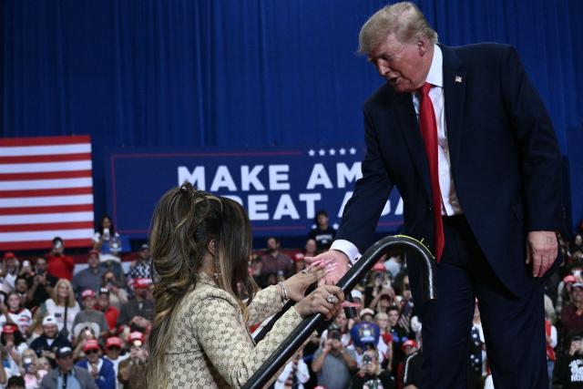 US President Donald Trump helps rapper Nicki Minaj on stage during a campaign rally at the McMorran Place Sports & Entertainment Center in Port Huron, Michigan, on October 25, 2026. (Photo by Brendan SMIALOWSKI / AFP)