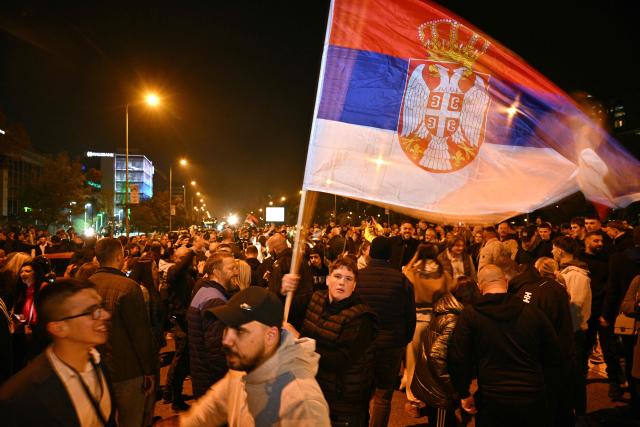 People wave a Serbian flag and gather in downtown Belgrade as they celebrate the outcome of the Serbian parliamentary elections, in Belgrade on October 25, 2026. Voters cast ballots in record numbers on October 25, 2026, with the country recording its highest parliamentary election turnout in more than three decades. Celebrations erupted on the streets of the capital; passing cars honked their horns as crowds began to party at the news that Serbia's ruling party had lost parliamentary snap elections. (Photo by Andrej ISAKOVIC / AFP)