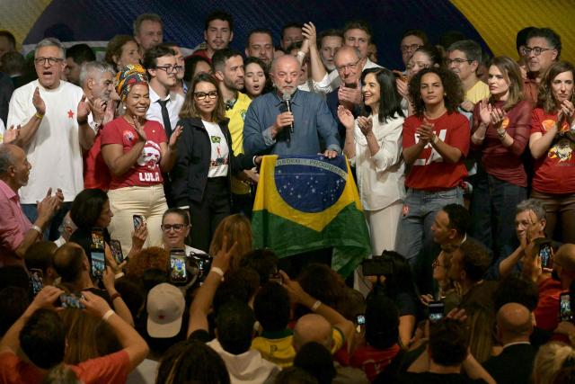 Brazil's President and re-election candidate for the Workers' Party (PT) Luiz Inacio Lula da Silva (C) speaks next to his wife, First Lady Rosangela da Silva (4nd L) and Vice President Geraldo Alckmin (5nd R) after knowing the first results of the presidential runoff election, in Sao Paulo, Brazil, on October 25, 2026. Lula da Silva pulled off a dramatic comeback on October 25, 2026, as he clinched election victory against right-wing senator Flavio Bolsonaro, who trounced him in the first round. (Photo by NELSON ALMEIDA / AFP)