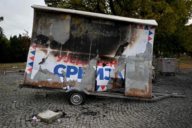A burned election campaign banner of the Serbian Progressive Party (SNS) is pictured at a pro-government encampment in a park opposite the Serbian Parliament in Belgrade on October 26, 2026, after crowds celebrating election results entered the site the previous night and dismantled tents that had occupied the area for months, setting them alight along with a number of cars. Serbia's student-led movement declared victory in parliamentary elections on October 25 ending 14 years in power for Aleksandar Vucic's right-wing populist party. The victory in the snap vote comes after nearly two years of anti-government protests sparked by the 2024 collapse of a canopy at Novi Sad railway station that killed 16 people. The disaster has been widely blamed on corruption and triggered some of Serbia's largest protests since the fall of strongman Slobodan Milosevic in 2000. (Photo by Andrej ISAKOVIC / AFP)
