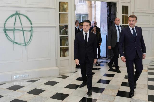EDITORS NOTE: Graphic content / France's President Emmanuel Macron (R) and the mayor of Marseille Benoit Payan, walk past an Anarchist symbol drawn on a wall inside the Marseille's Town Hall which was recently vandalized in Marseille, southern France on October 26, 2026, during a visit to notice the 'return of republican order' after the violence and looting that punctuated the citizen mobilization of October 17, 2026. Protests by high school students over learning conditions sparked a movement that has since spread nationwide, fuelled by broader anger over the rising cost of living. (Photo by Aurelien Morissard / POOL / AFP)