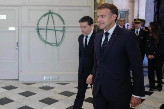 EDITORS NOTE: Graphic content / France's President Emmanuel Macron (R) and the mayor of Marseille Benoit Payan, walk past an Anarchist symbol drawn on a wall inside the Marseille's Town Hall which was recently vandalized in Marseille, southern France on October 26, 2026, during a visit to notice the 'return of republican order' after the violence and looting that punctuated the citizen mobilization of October 17, 2026. Protests by high school students over learning conditions sparked a movement that has since spread nationwide, fuelled by broader anger over the rising cost of living. (Photo by Aurelien Morissard / POOL / AFP)