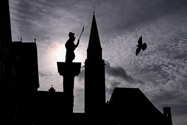 A pigeon flies over the central Roemerberg square in front of the Evangelical Lutheran St Nicholas Church (C) and the Minerva Fountain in Frankfurt am Main, western Germany, on October 26, 2026. (Photo by Kirill KUDRYAVTSEV / AFP)