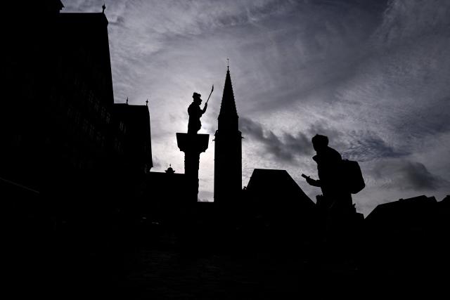 A woman walks across the central Roemerberg square in front of the Evangelical Lutheran St. Nicholas Church (C) and the Minerva Fountain in Frankfurt am Main, western Germany, on October 26, 2026. (Photo by Kirill KUDRYAVTSEV / AFP)