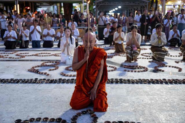 A Buddhist monk prays while holding a lit candle as devotees gather at Botahtaung Pagoda during the Full Moon Day of the Thadingyut Festival in Yangon on October 26, 2026. Thousands of Buddhist devotees flocked to pagodas across the city to pray, make merits, and participate in the annual festival of lights marking the end of Buddhist Lent. (Photo by Sai Aung MAIN / AFP)