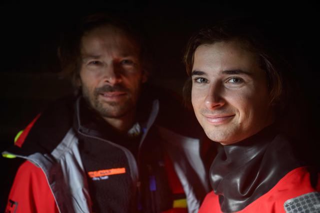 French skipper Romain Pilliard (L) poses with his son French skipper Titouan Pilliard, 20, the youngest of the fleet, aboard the Vintage Mono 'Use It Again for Youth' at the village of the Route du Rhum - Destination Guadeloupe, a few days prior to the start of this solo sailing race from Saint-Malo, western France to Pointe-a-Pitre in the French overseas island of Guadeloupe, in Saint-Malo, western France, on October 26, 2026. (Photo by Loic VENANCE / AFP)