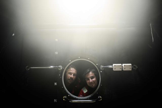 French skipper Romain Pilliard (L) poses with his son French skipper Titouan Pilliard, 20, the youngest of the fleet, aboard the Vintage Mono 'Use It Again for Youth' at the village of the Route du Rhum - Destination Guadeloupe, a few days prior to the start of this solo sailing race from Saint-Malo, western France to Pointe-a-Pitre in the French overseas island of Guadeloupe, in Saint-Malo, western France, on October 26, 2026. (Photo by Loic VENANCE / AFP)