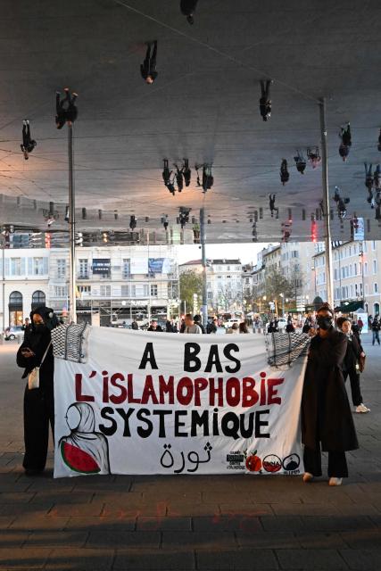 People hold a banner which reads "Down with systemic Islamophobia" ahead of a tribute to the victims of the Trappes attacks, in Marseille, on October 26, 2026. A man suspected of a gun attack in the Paris suburbs that killed Pengo Bossio Wangi and wounded five other persons has left custody and been placed in a psychiatric unit for observation, French anti-terror prosecutors said on October 25, 2026. The 39-year-old suspect, partly identified as Kevin T., was arrested on October 23, in possession of a submachine gun and tear-gas grenades in his car, shortly after the victims were shot as a vehicle drove through the working-class town of Trappes and neighbouring La Verriere. (Photo by Justine MEDDAH / AFP)