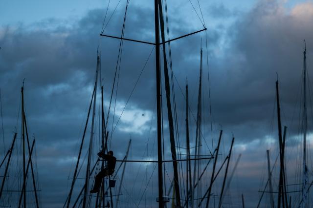 A crew member works on a mast in the harbour of Saint-Malo, western France on October 26, 2026, a few days before the start of the 13th Route du Rhum - Destination Guadeloupe. From Saint-Malo in Brittany to Pointe-à-Pitre in Guadeloupe, 115 skippers across 6 classes will take the start on November 1, 2026, in this solo transatlantic sailing race. (Photo by Martin BUREAU / AFP)