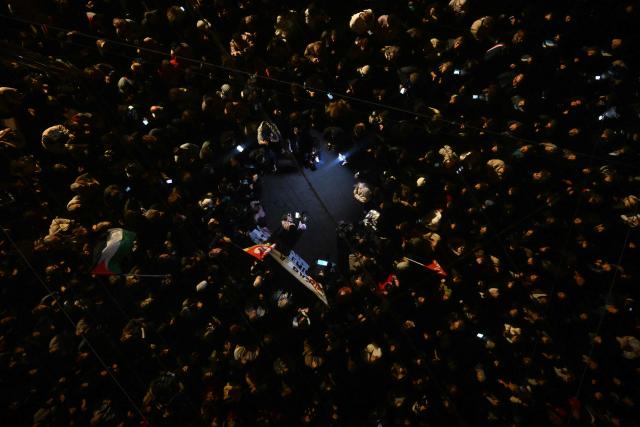 This reflected image shows a speaker addressing the crowd during a tribute to the victims of the Trappes attacks, in the Old Port in Marseille, on October 26, 2026. A man suspected of a gun attack in the Paris suburbs that killed Pengo Bossio Wangi and wounded five other persons has left custody and been placed in a psychiatric unit for observation, French anti-terror prosecutors said on October 25, 2026. The 39-year-old suspect, partly identified as Kevin T., was arrested on October 23, in possession of a submachine gun and tear-gas grenades in his car, shortly after the victims were shot as a vehicle drove through the working-class town of Trappes and neighbouring La Verriere. (Photo by Justine MEDDAH / AFP)