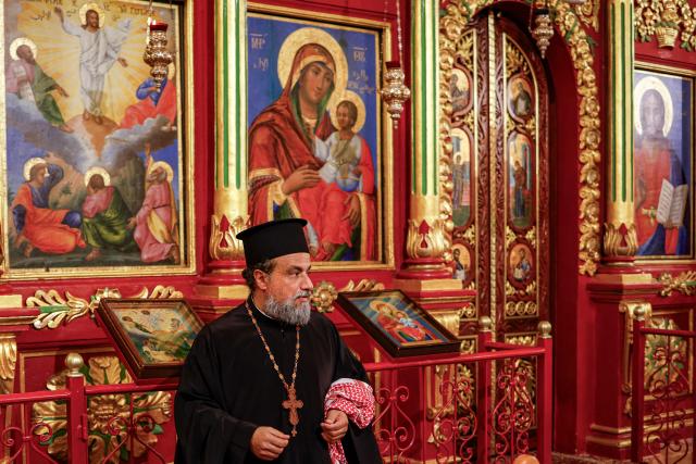 A priest holds a Jordanian keffiyeh scarf in his hand during a memorial service at the Greek Orthodox Church of the Transfiguration in the city of Ramallah in the Israeli-occupied West Bank, on October 26, 2026, in solidarity with the victims killed in an attack on the church in Jordan's village of Hammoud on October 23. On October 23, gunmen stormed the compound of the Greek Orthodox St George's Church in the village of Hammoud in Karak governorate during a funeral procession, killing nine. Karak is home to a significant Christian community in Muslim-majority Jordan, where Christians make up between two and three percent of the population. (Photo by Zain JAAFAR / AFP)