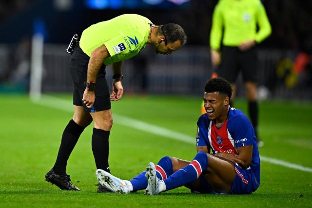 French referee Jerome Brisard (L) checks on PSG's French forward #14 Desire Doue (R) as he sits injured on the pitch during the French L1 football match between Paris Saint-Germain (PSG) and Olympique Lyonnais (OL) at the Parc des Princes stadium in Paris on October 26, 2026. (Photo by JULIEN DE ROSA / AFP)