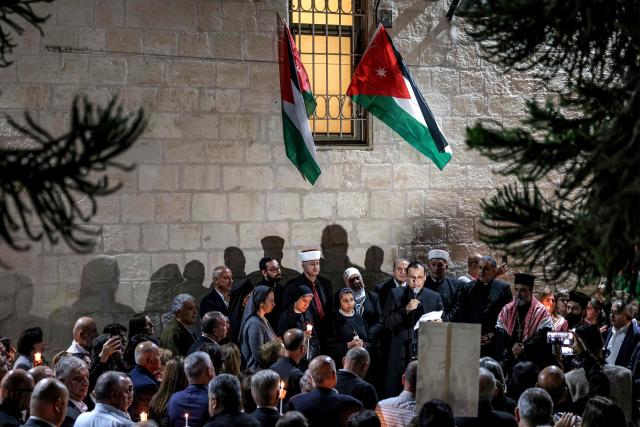 Mourners listen as a Christian clergyman speaks during a vigil at the Greek Orthodox Church of the Transfiguration in the Palestinian city of Ramallah in the Israeli-occupied West Bank, on October 26, 2026, in solidarity with the victims of an attack on the Church of St George in Jordan's village of Hammoud on October 23. On October 23, gunmen stormed the compound of the Greek Orthodox St George's Church in the village of Hammoud in Karak governorate during a funeral procession, killing nine. Karak is home to a significant Christian community in Muslim-majority Jordan, where Christians make up between two and three percent of the population. (Photo by Zain JAAFAR / AFP)