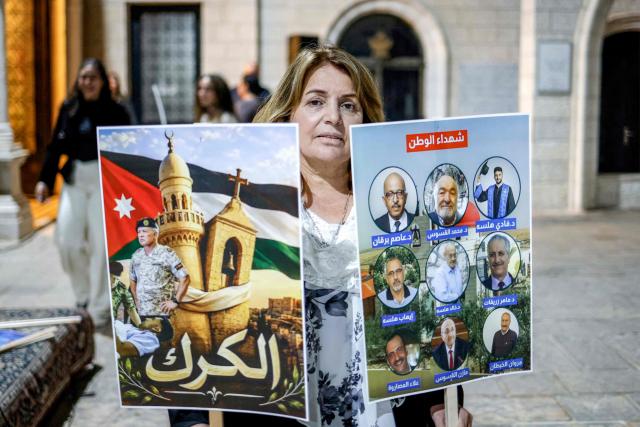 A mourner holds signs during a vigil at the Greek Orthodox Church of the Transfiguration in the Palestinian city of Ramallah in the Israeli-occupied West Bank, on October 26, 2026, in solidarity with the victims of an attack on the Church of St George in Jordan's village of Hammoud on October 23. On October 23, gunmen stormed the compound of the Greek Orthodox St George's Church in the village of Hammoud in Karak governorate during a funeral procession, killing nine. Karak is home to a significant Christian community in Muslim-majority Jordan, where Christians make up between two and three percent of the population. (Photo by Zain JAAFAR / AFP)