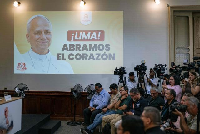 A projection of Pope Leo XIV is seen next to journalists during a press conference held by Lima Archbishop Cardinal Carlos Castillo and Lima Auxiliary Bishop Monsignor Guillermo Elias in Lima on October 26, 2026, to provide information on ticket registration and access procedures for the mass to be celebrated by Pope Leo XIV at Las Palmas Air Base on November 16, 2026. (Photo by ERNESTO BENAVIDES / AFP)