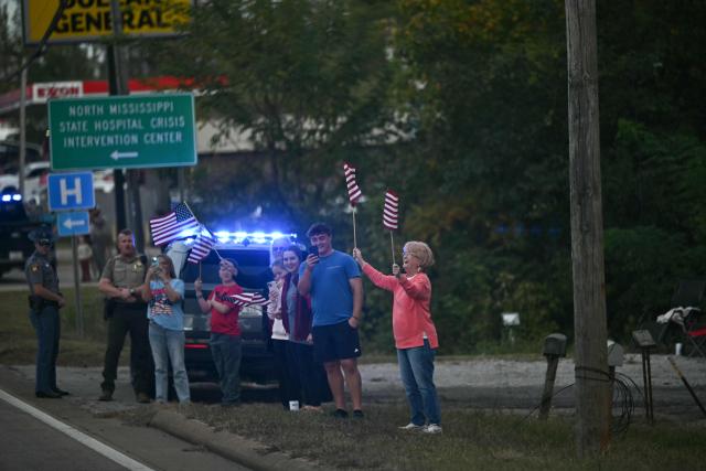 Supporters wave flags as they watch the motorcade of US President Donald Trump drive past in Corinth, Mississippi, on October 26, 2026. Trump is travelling to Mississippi to speak at a midterm campaign rally. (Photo by Kent NISHIMURA / AFP)