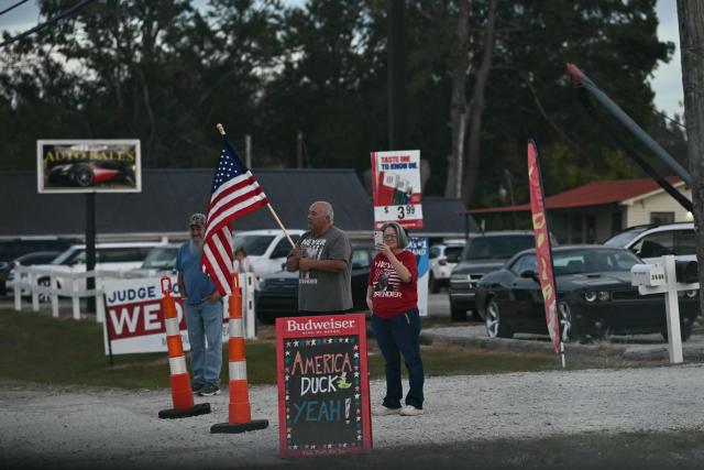 Supporters watch the motorcade of US President Donald Trump drive past in Corinth, Mississippi, on October 26, 2026. Trump is travelling to Mississippi to speak at a midterm campaign rally. (Photo by Kent NISHIMURA / AFP)