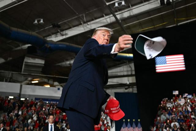 US President Donald Trump throws hats into the crowd before speaking at a midterm campaign rally at Crossroads Arena in Corinth, Mississippi on October 26, 2026. President Trump is holding the campaign rally to support the re-election campaign of US Senatory Cindy Hyde-Smith (R-MS). (Photo by Kent NISHIMURA / AFP)