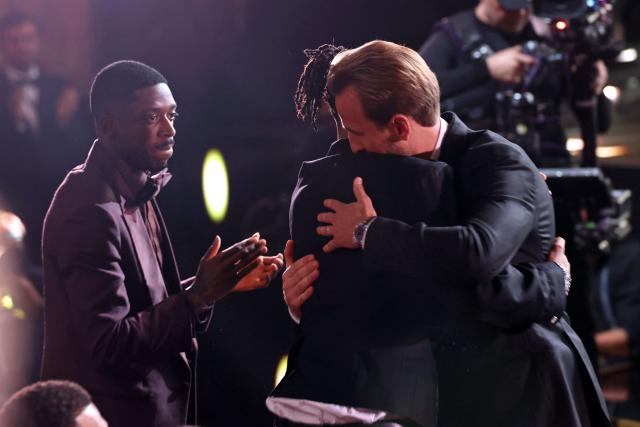 France and Paris Saint Germain forward Ousmane Dembele (L) applauds as France and Bayern Munich forward Michael Olise (C) and England and Bayern Munich forward Harry Kane (R) embrace after Kane is announced as the winner of Ballon d'Or award for the best male footballer during the 2026 Ballon d'Or France Football award ceremony at the Palladium Theatre in London on October 26, 2026. (Photo by FRANCK FIFE / AFP)