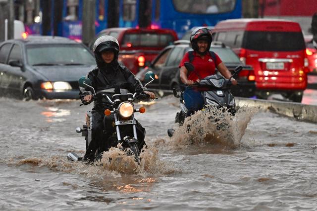 Motorcycles make their way through flooded waters after heavy rains in north of Guayaquil, Ecuador on October 26, 2026. (Photo by MARCOS PIN / AFP)