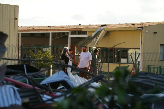 Residents stand next to a house damaged by a tornado in Requinoa, O'Higgins Region, Chile on October 26, 2026. Severe weather affected central Chile as strong winds and unstable atmospheric conditions impacted several communities in the region. (Photo by PABLO MARDONES / AFP)