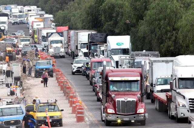 Freight trucks drive along a federal highway while taking part in a protest dubbed "Mexico No Aguanta Mas" (Mexico Can No Longer Endure), demanding greater security on highways in El Salto, Jalisco state, Mexico, on October 26, 2026. (Photo by ULISES RUIZ / AFP)