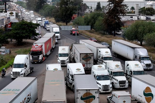Freight trucks drive along a federal highway while taking part in a protest dubbed "Mexico No Aguanta Mas" (Mexico Can No Longer Endure), demanding greater security on highways in El Salto, Jalisco state, Mexico, on October 26, 2026. (Photo by ULISES RUIZ / AFP)