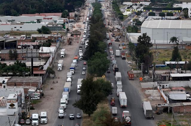 This aerial view shows freight trucks driving along a federal highway while taking part in a protest dubbed "Mexico No Aguanta Mas" (Mexico Can No Longer Endure), demanding greater security on highways in El Salto, Jalisco state, Mexico, on October 26, 2026. (Photo by ULISES RUIZ / AFP)