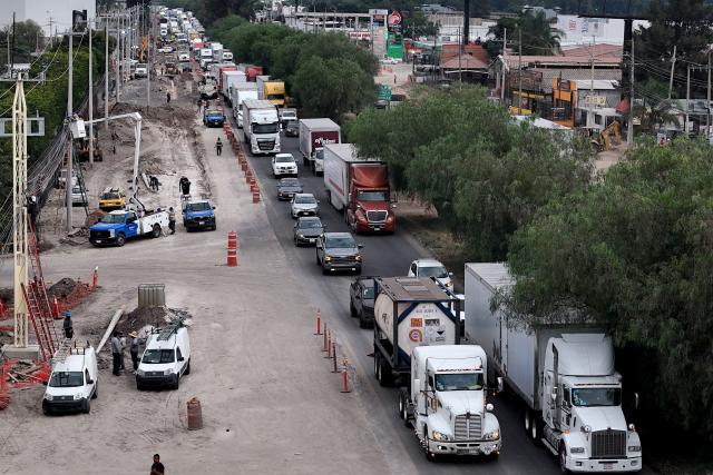 This aerial view shows freight trucks driving along a federal highway while taking part in a protest dubbed "Mexico No Aguanta Mas" (Mexico Can No Longer Endure), demanding greater security on highways in El Salto, Jalisco state, Mexico, on October 26, 2026. (Photo by ULISES RUIZ / AFP)