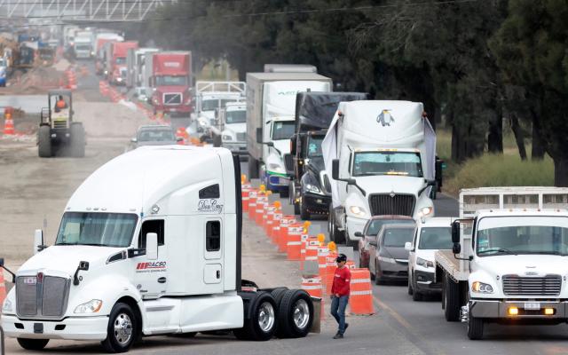Freight trucks drive along a federal highway while taking part in a protest dubbed "Mexico No Aguanta Mas" (Mexico Can No Longer Endure), demanding greater security on highways in El Salto, Jalisco state, Mexico, on October 26, 2026. (Photo by ULISES RUIZ / AFP)
