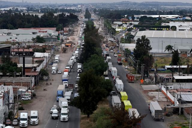This aerial view shows freight trucks driving along a federal highway while taking part in a protest dubbed "Mexico No Aguanta Mas" (Mexico Can No Longer Endure), demanding greater security on highways in El Salto, Jalisco state, Mexico, on October 26, 2026. (Photo by ULISES RUIZ / AFP)