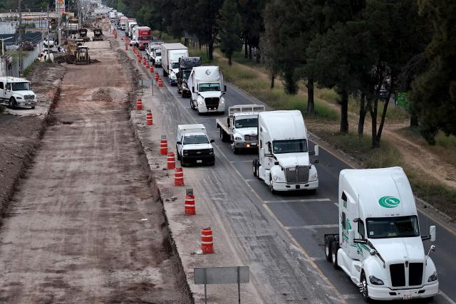 This aerial view shows freight trucks driving along a federal highway while taking part in a protest dubbed "Mexico No Aguanta Mas" (Mexico Can No Longer Endure), demanding greater security on highways in El Salto, Jalisco state, Mexico, on October 26, 2026. (Photo by ULISES RUIZ / AFP)