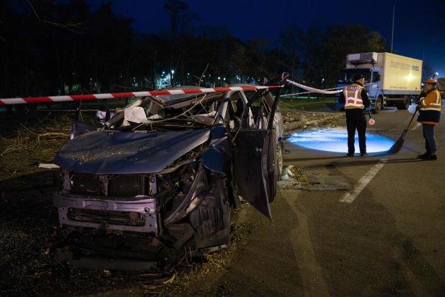A municipal worker speaks to a police officer near a destroyed car on a road in Kyiv on October 27, 2026, following a Russian missile strike. (Photo by Genya SAVILOV / AFP)